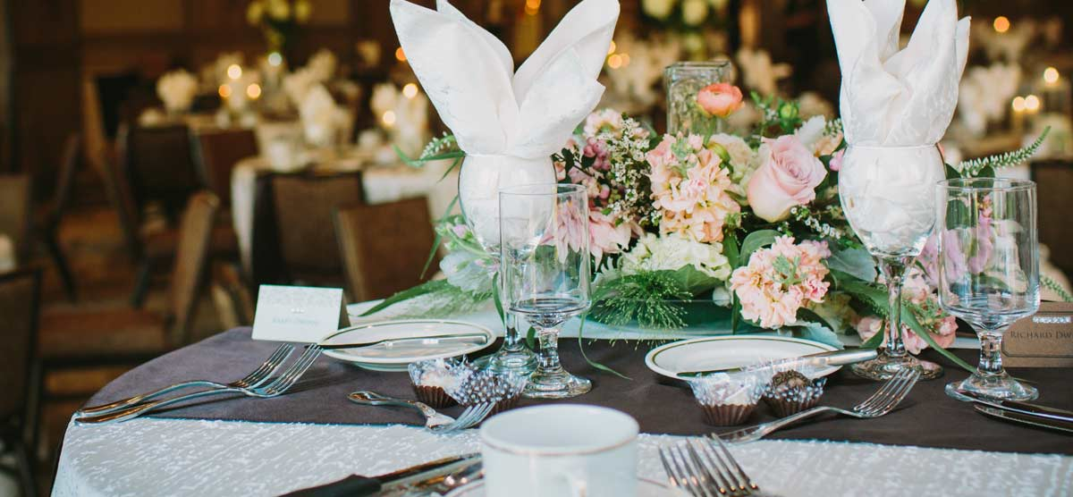 Table with floral centerpiece and cutlery set for a wedding reception in the Grand Hall