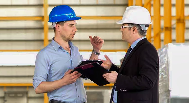 Two people in hard hats on jobsite talking