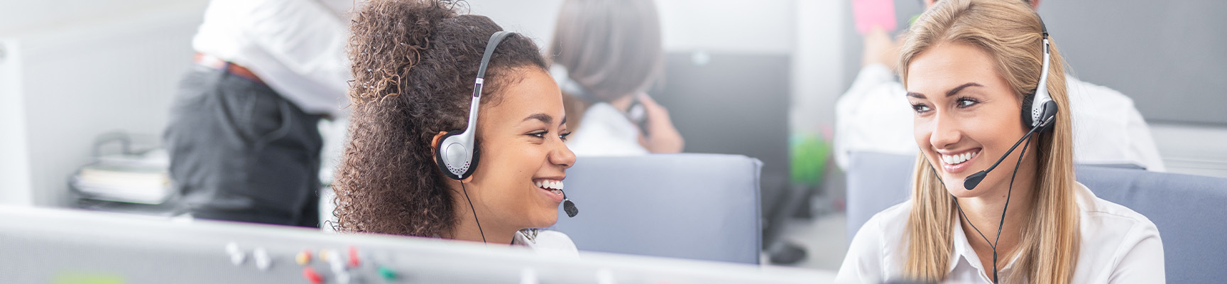 Two women on headsets working on computers