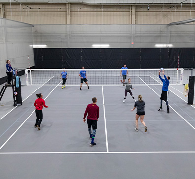 Fieldhouse volleyball court with people playing.