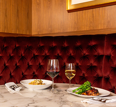 Bowl of pasta with red wine and plate of chicken with white wine. 