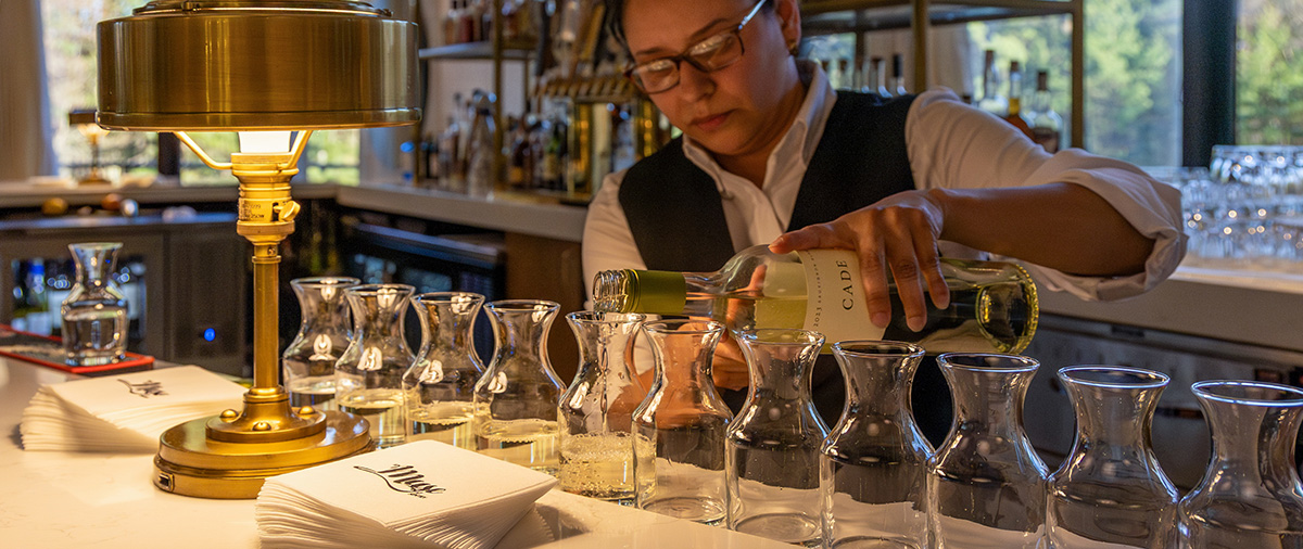 Server pouring wine into small containers on the Muse bar