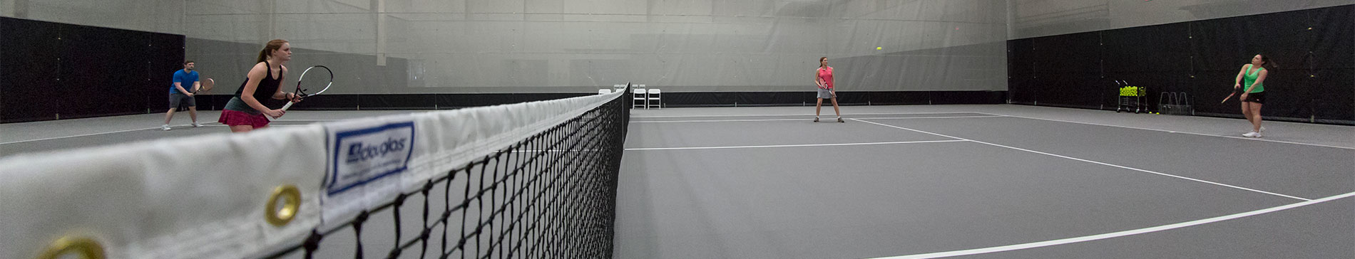 Tennis court net and players on a court in the SentryWorld fieldhouse