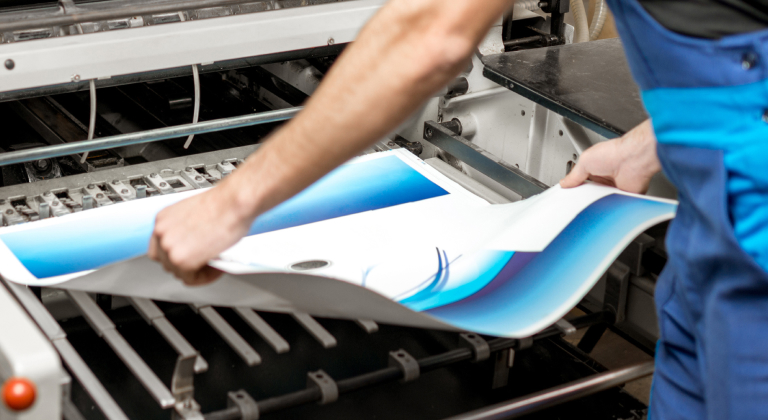 Worker pulling a sheet of paper from a printer