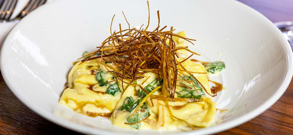 Green Chili Artichoke Tortellacci plated on a table at Muse