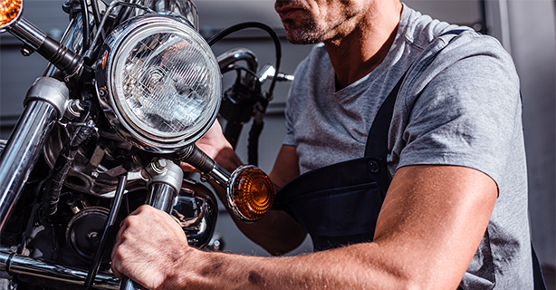 Cropped view of mechanic fixing motorcycle headlamps in garage
