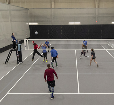 Volleyball player passing the ball to a team member in the SentryWorld fieldhouse