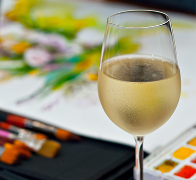 Glass of wine with a painting, paint brushes, and a paint pallet