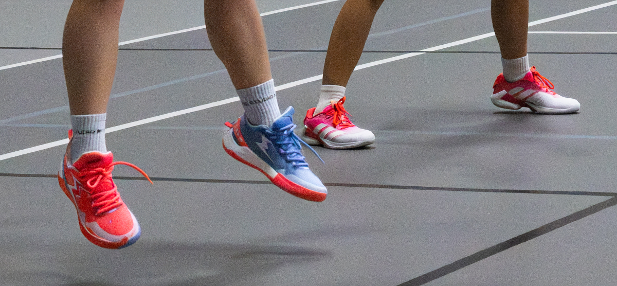 Close-up of players’ feet in colorful athletic shoes on an indoor court.