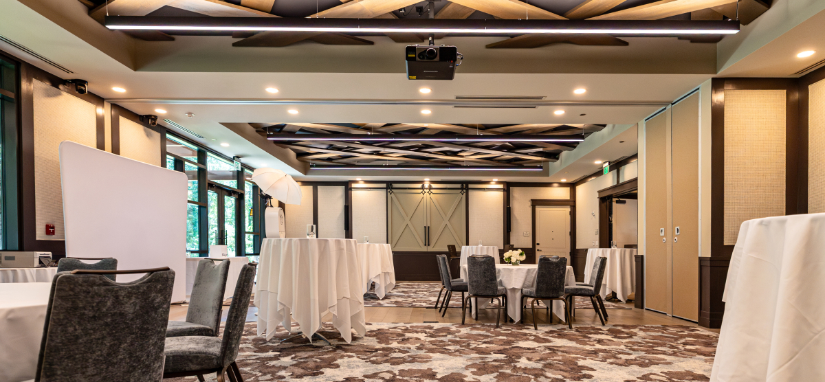 Event room with round tables, high-top tables, a photo booth, and a decorative ceiling.