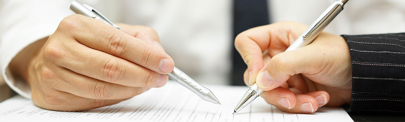 Two people with pens reviewing document