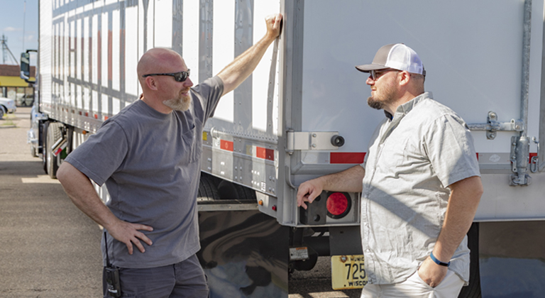 Two people talking outside semi trailer truck