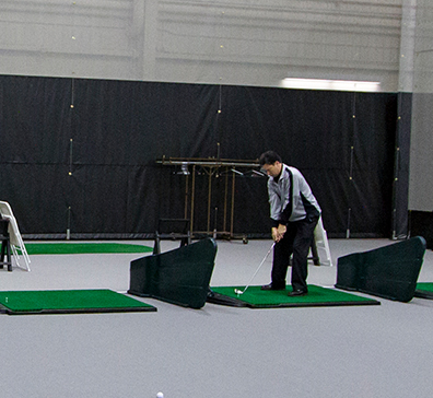 Golfer hitting off an indoor map in the indoor range at SentryWorld