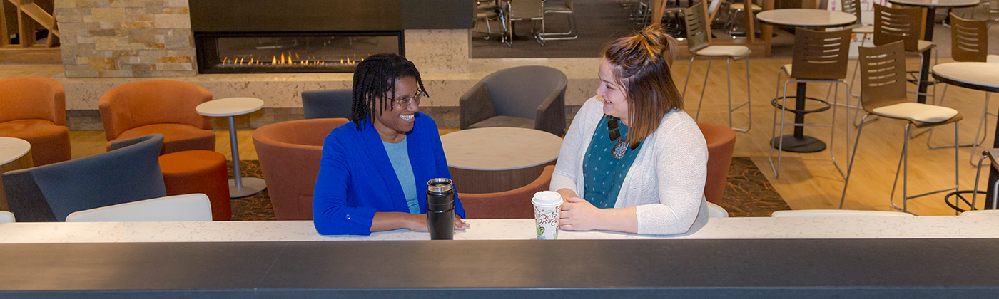 Two people sitting in the Sentry cafeteria drinking coffee