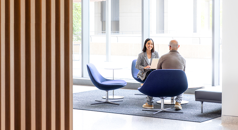 two people sitting and talking in an office setting