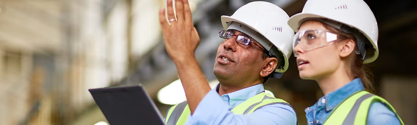 Two people in hard hats surveying