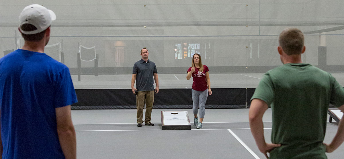 Two teams playing bean bag toss against each other in the SentryWorld fieldhouse