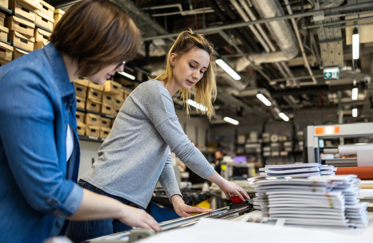 Two workers assembling printed books.
