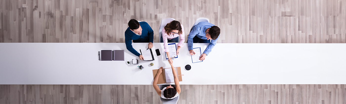 Aerial view of three people interviewing a candidate.