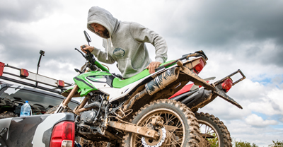 Man with dirt bikes in bed of truck.