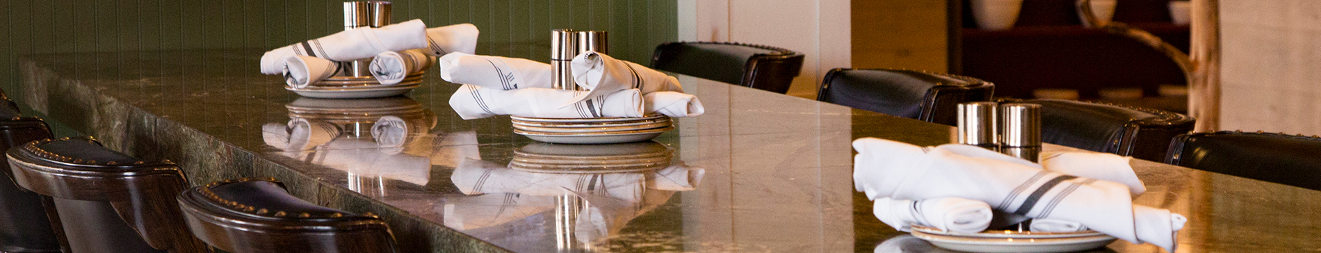 Plates and napkins set out on a long table with chairs