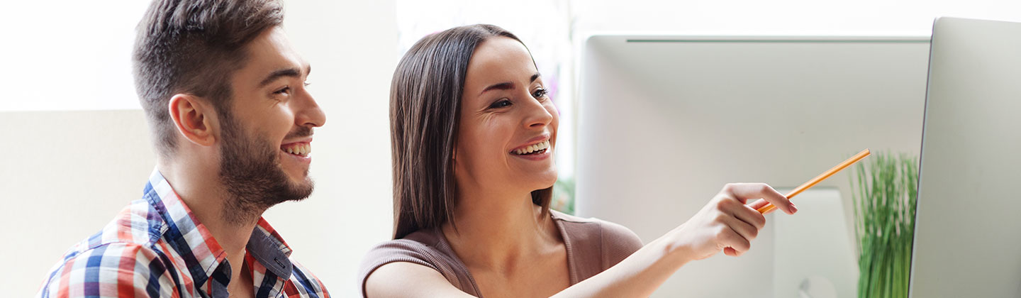 Two people smiling looking at monitor