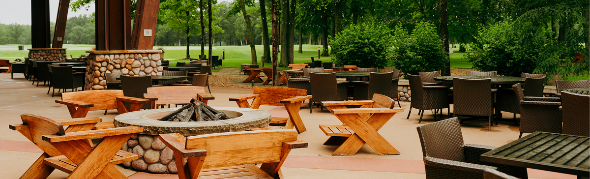 Outdoor patio with a fire pit, various seating, and a golf course in the background.