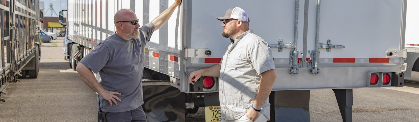 Two people talking outside semi trailer truck