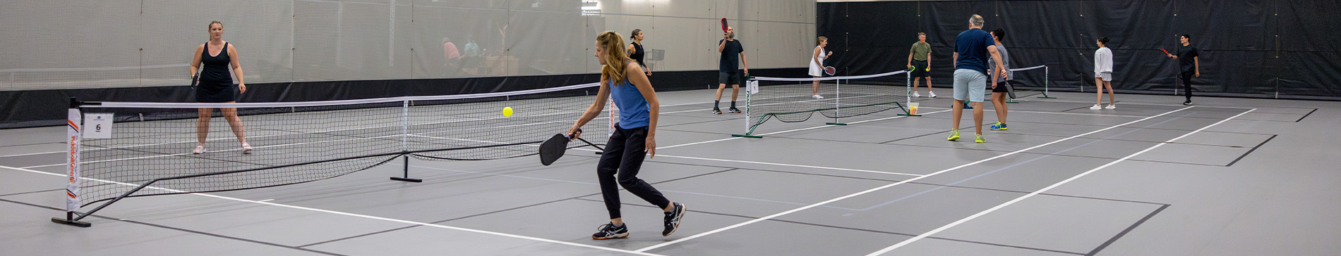 Fieldhouse pickleball courts with players playing pickleball. 