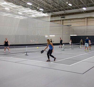 Fieldhouse pickleball courts with players playing pickleball. 