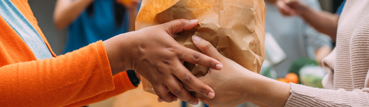 Close up of hands handing over a bag of food from one person to another