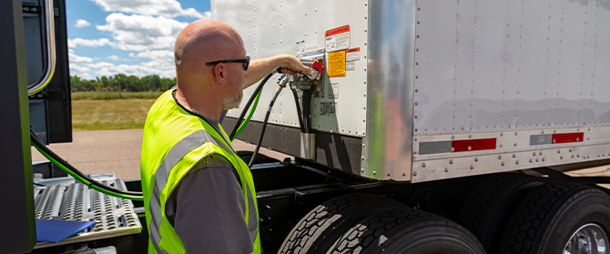 Man checking and adjusting connection on semi trailer truck