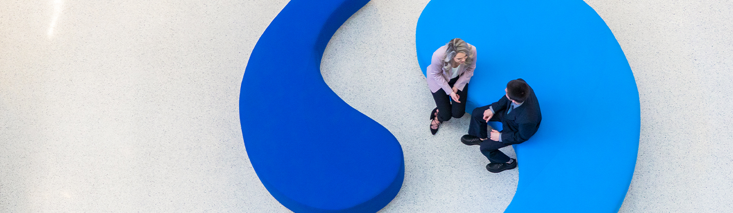 Two people sitting on the Sentry benches that are in the shape of quotation marks