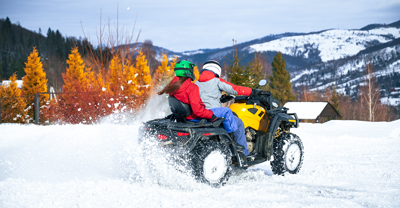 Two people riding an ATV in snow