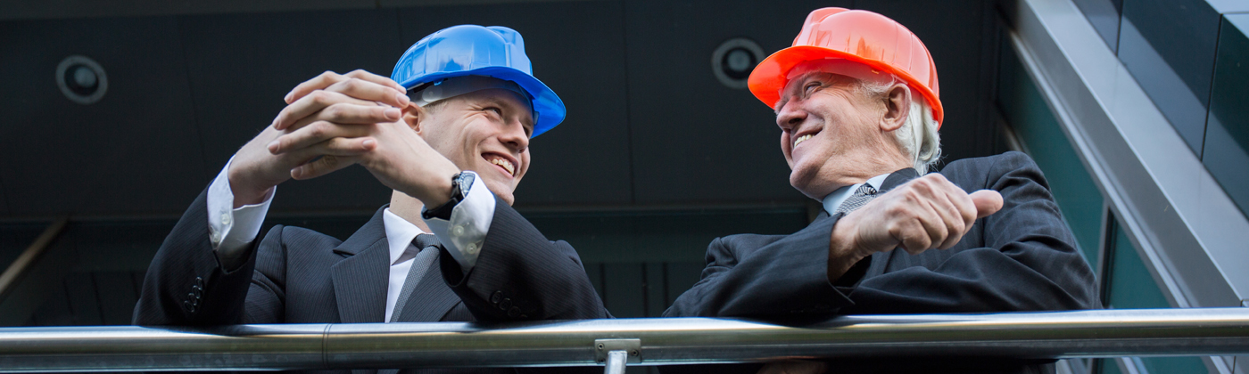 Two business men in suits and hard hats smiling