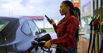 Woman on phone pumping gas into car