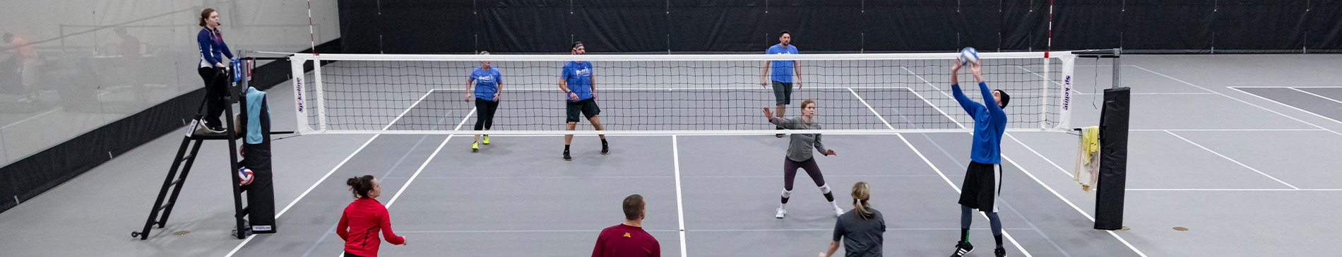 Fieldhouse volleyball court with people playing.