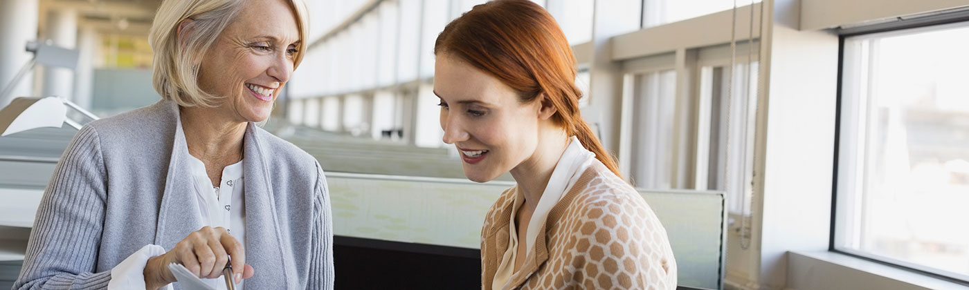 Two women in meeting smiling looking at documents