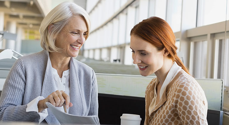 Two women in meeting smiling looking at documents