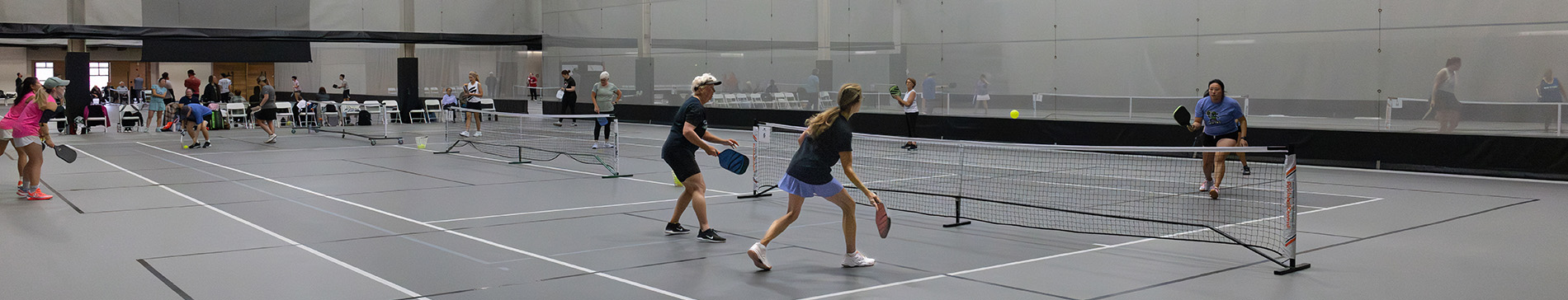 Fieldhouse pickleball courts with players playing pickleball. 