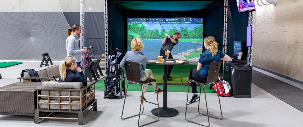 People playing the golf simulator in the indoor golf range at SentryWorld