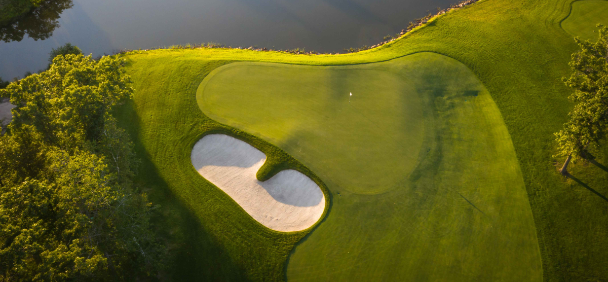 Golf course green with sand trap and water. 