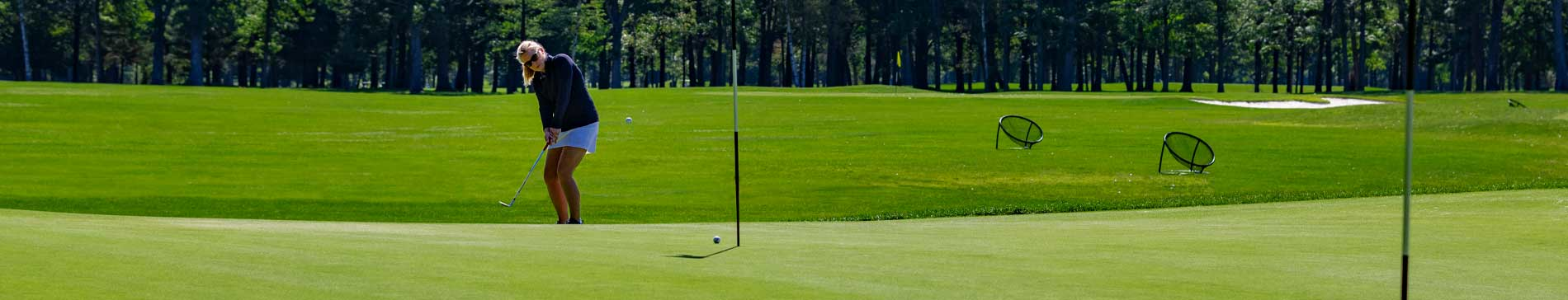 Woman chipping onto practice green at SentryWorld