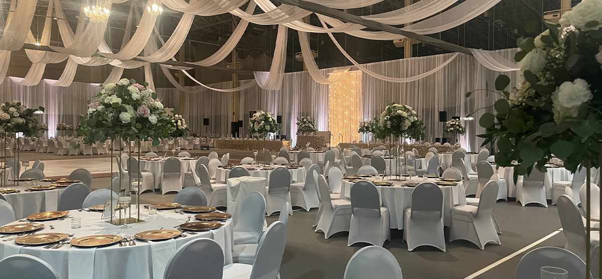 carousel-wedding-venue-fieldhouse-1-1200x556 Many round tables and chairs set up for a wedding in the fieldhouse.