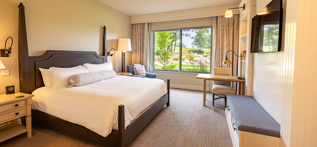 carousel-suite-golf-view-king-queen-1-1200x556 King bedroom with desk area and bench.