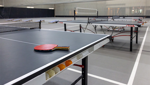 Table tennis tables, bean bag boards and tennis set up for a fieldhouse special event.