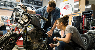 A man and a woman looking over a used motorcycle