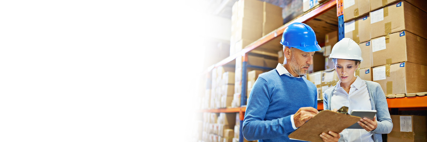 Two business professionals wearing safety helmets in a warehouse