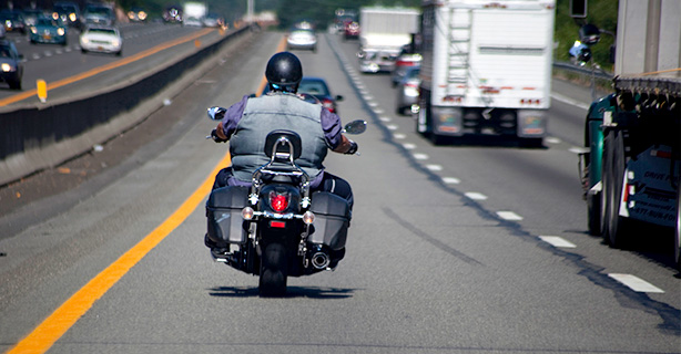 Person riding motorcycle on highway near semi trucks