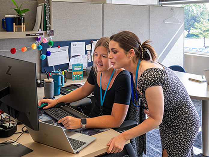 Two women working together on computers.